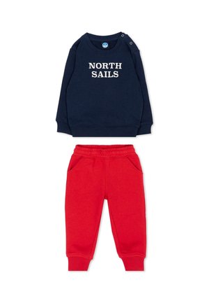 Felpa blu navy a maniche lunghe con testo "NORTH SAILS" e pantaloni rossi con vita elastica e tasche, stesi su sfondo bianco.