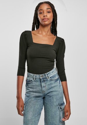 Černý dlouhý rukáv bodysuit s hranatým výstřihem, vyrobený z elastického materiálu. Spárovaný se světle modrými džínami s vysokým pasem a postranními kapsami.