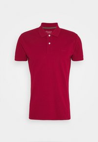 Polo-shirt en coton organique rouge, manches courtes, patte de boutonnage à deux boutons, logo discret sur la poitrine, col classique, texture lisse.