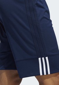 Marineblaue Sportshorts aus atmungsaktivem Material, mit weißen drei Streifen am Seitenrand und einem bequemen, elastischen Bund.