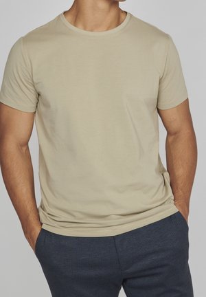 Beige kortærmet t-shirt med rund hals, lavet af et glat stof. T-shirten sidder tætsiddende til kroppen, med et enkelt design og syninger.
