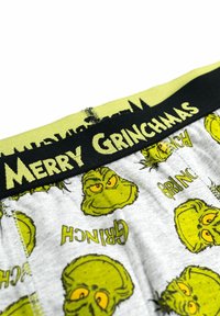 Boxer in cotone grigio con un motivo a fumetti del Grinch e la scritta "Merry Grinchmas" su una cintura elastica nera.