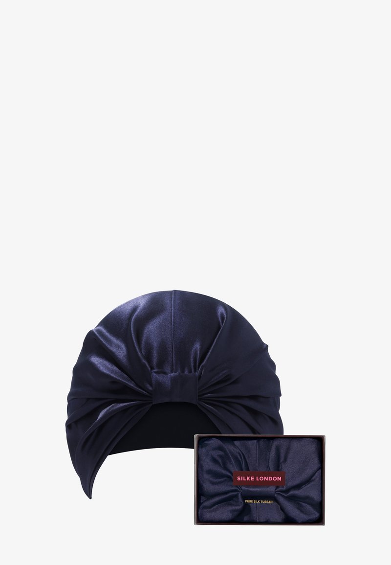 Marineblå silketurban med en vridd frontdesign, med glatt tekstur og en medfølgende eske med "SILKE LONDON" merke.