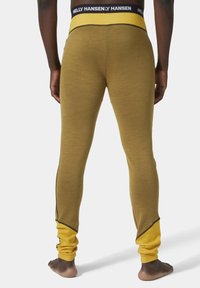 Olivově zelené legíny s žlutým pásem a černým logem. Mají kontrastní švy a těsně přiléhavý střih. Texturovaná tkanina.