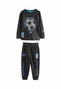 Camiseta negra de manga larga con gráfico de balón de fútbol, texto azul y pantalones a juego con cinturilla elástica y estampados en las piernas. Tejido de algodón.