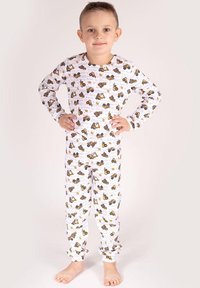 Biały komplet piżamy z powtarzającym się wzorem żółtych i brązowych pojazdów budowlanych. Długie rękawy i elastyczne ściągacze na spodniach.