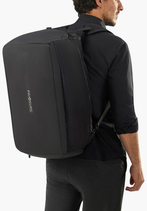 Black rectangular backpack with a textured surface, adjustable straps, and printed logo. Features a cushioned design for comfort.