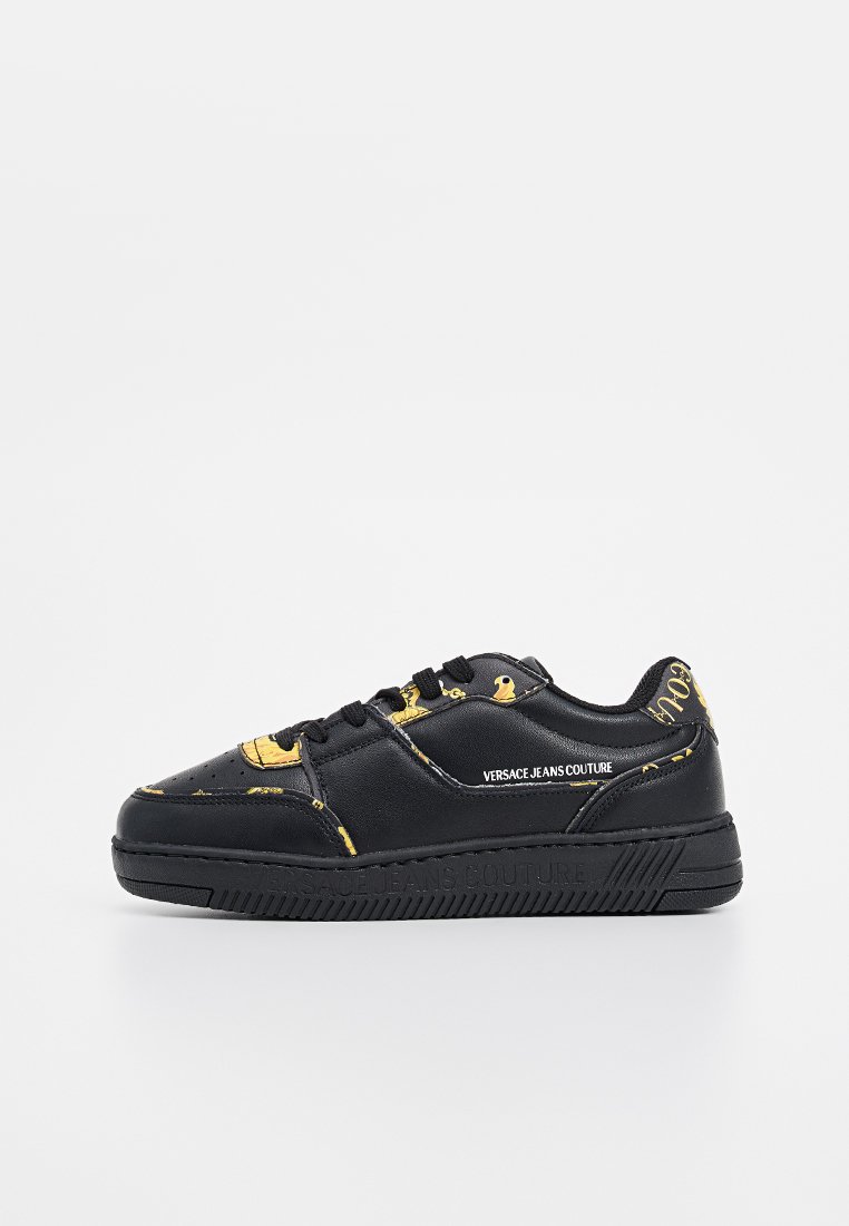 Zapatillas negras con patrón de patito amarillo, parte superior de cuero liso, puntera redonda, diseño de cierre con cordones y suela de goma con un dibujo texturizado.