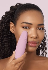 Rosa ansiktsrengöringsapparat med en mjuk, ergonomisk design. Har knappar för drift och en strukturerad topp för skonsam rengöring.