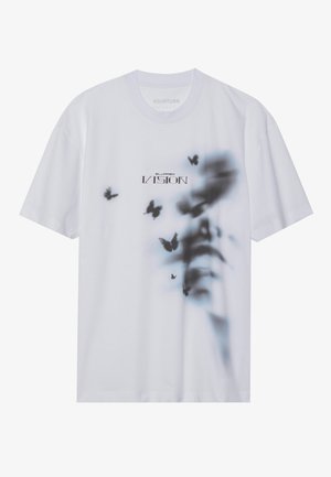 T-shirt branca de algodão com uma impressão desfocada de borboleta em preto. Texto "VISÃO DESFOCADA" em fonte escura ao centro.