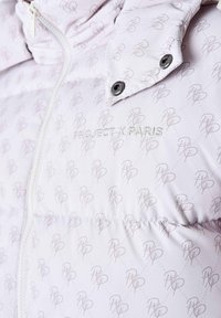 Giacca imbottita bianca con un delicato motivo a logo rosa, dotata di chiusura con zip, colletto alto e accenti in metallo argentato. Ricamo "PROJECT X PARIS."