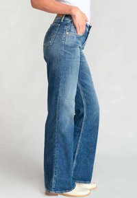 Lichtblauwe denim jeans met een ontspannen, wijde pasvorm. Heeft een middelhoge taille, voor- en achterzakken en subtiele vervaging.