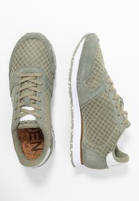 Grüne Sneaker aus Mesh und Wildleder mit strukturiertem Obermaterial, Schnürverschluss, weißer Sohle mit gesprenkelten Akzenten und Korkfußbett.