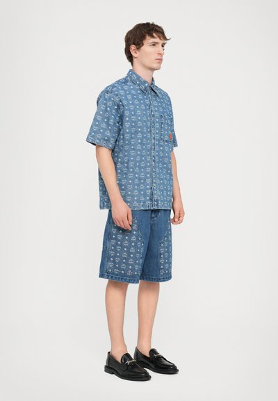 Jeansskjorta och shorts-set med en blå, mönstrad design och en ficka på skjortan. Kombinerat med svarta loafers.