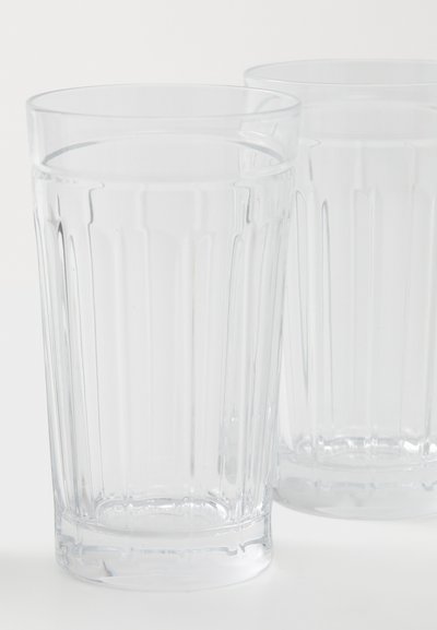 Δύο διάφανα πλαστικά ποτήρια με κάθετη ριγέ υφή, κυλινδρικό σχήμα και ομαλή άκρη, τοποθετημένα κοντά το ένα στο άλλο.