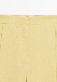 Lichtgele linnen broek met een platte voorkant, subtiele plooien en een gladde textuur, voorzien van een standaard tailleband en zijzakken.