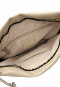 Beige leather handbag interior with a textured finish, featuring a zipped pocket, a flat pocket, and a smooth lining. Black zipper accents.