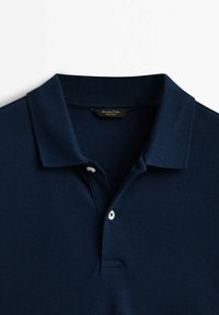Polo bleu marine avec un col classique et deux boutons blancs sur la patte, posé à plat sur un fond blanc.