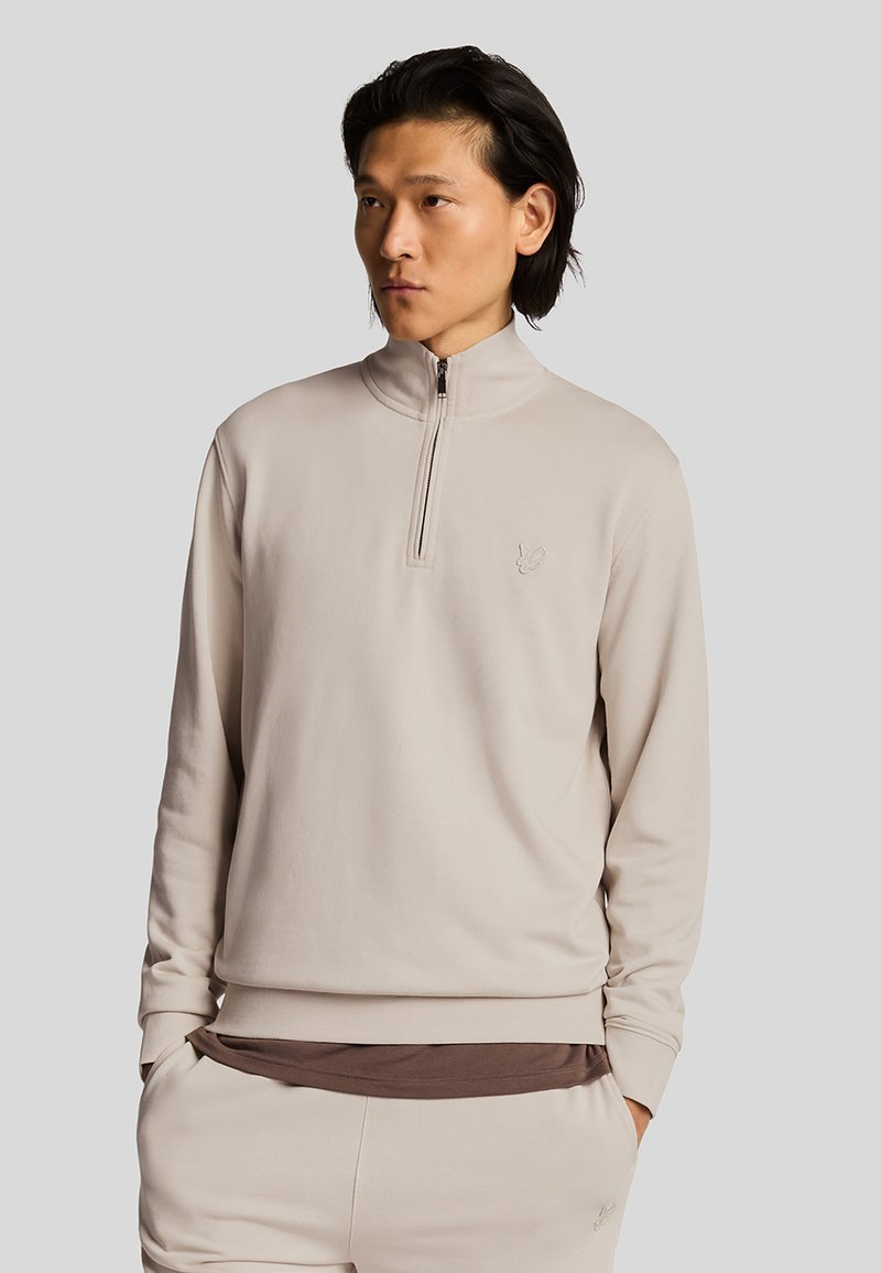 Licht beige half-zip sweater gemaakt van een gladde stof, met een tonale logo op de borst en een lose fit met lange mouwen.