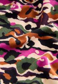 Multicolored fabric featuring a camouflage pattern with shades of pink, green, brown, and black on a cream background, textured and soft.