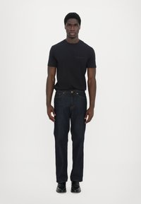Svart bomulls t-skjorte og mørkeblå denimjeans. Slim fit med en glatt tekstur. Jeansene har oransje søm og knappelukking.