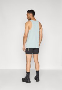 Jasnoniebieska sportowa koszulka bez rękawów, czarne szorty, czarne trampki i czarne skarpetki. Gładki materiał, minimalne szwy oraz detal z logo na szortach.