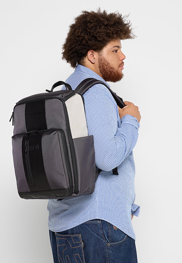 Zaino con un design nero e grigio, dotato di pannelli testurizzati, una tasca frontale e spallacci regolabili, realizzato in un tessuto resistente.