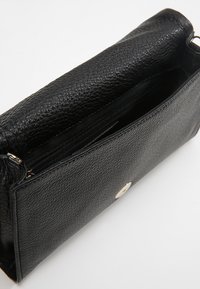 Czarna skórzana torba na ramię o fakturowanej powierzchni, z zapięciem na suwak i akcentami w kolorze złotym. Wnętrze jest przestronne z osobną kieszenią.