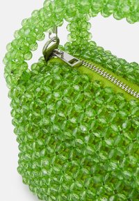 Vihreä helmisalkku pyöreällä muotoilulla. Valmistettu muovipeleistä, jossa on hopeinen vetoketju ja kangasvuori. Jännittävä ja eläväinen muotoilu.