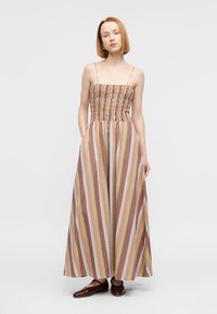 Μάξι φόρεμα με ριγέ μοτίβο και κορσάζ με σφηκοφωλιά, που διαθέτει κάθετες ρίγες σε πορτοκαλί, κίτρινο, μπλε και ροζ πάνω σε ανοιχτό φόντο.