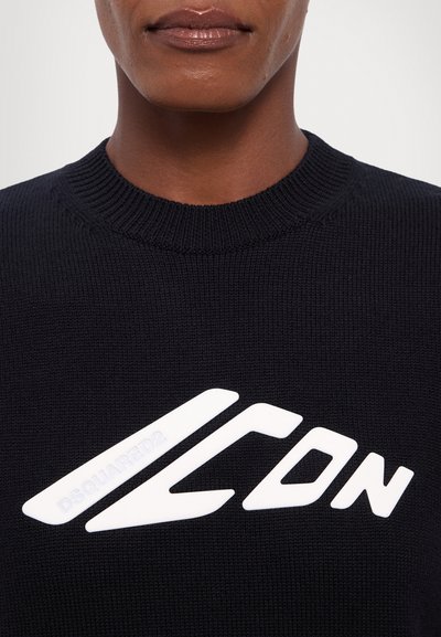 Zwarte gebreide trui met een opvallend wit "ICON" logo met hoeke lijnen en een gestructureerde afwerking bij de hals.