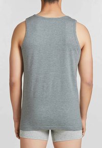 Canottiera grigia in cotone con scollatura rotonda, design senza maniche e texture sottile, vista da dietro. Abbinata a pantaloni corti grigi chiari.