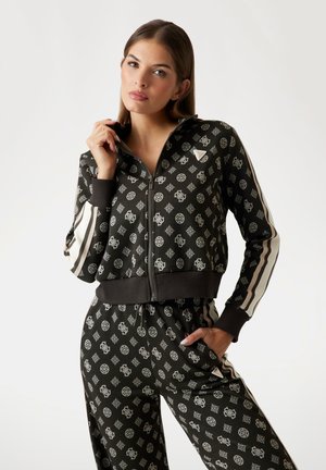 Black zip-up jacket with white geometric patterns, ribbed cuffs, and matching pants. Features vertical white stripes along sleeves.