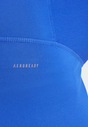 AeroReady majica bez rukava u vibrantnoj plavoj boji, s glatkom teksturom, ravnim šavovima i vidljivim logotipom uz bočnu stranu.
