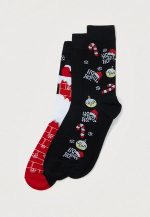 Három pár karácsonyi motívumú zokni, amelyek cukorpálcákat, hópelyheket, "Ho Ho Ho" feliratot, Mikulás sapkákat, karácsonyi pudingot és kandalló mintázatot tartalmaznak.