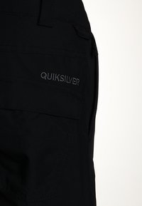 Sorte stofshorts med sidelommer, prydet med Quiksilver-logoet broderet i grå. Glat tekstur og praktisk design til aktiv brug.