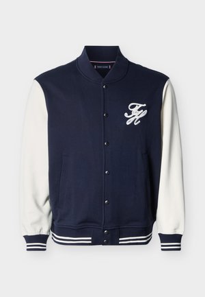 Veste universitaire bleu marine avec manches blanches, poignets et ourlet rayés, boutons pression, et logo blanc "FH" sur la poitrine gauche.