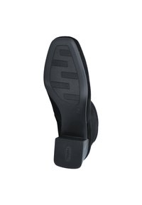 Chaussure en suede noir avec une semelle en caoutchouc plate, présentant un motif de semelle texturé et un talon carré. Pas d'ornementation ou de logos visibles.