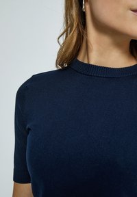 Mörkblå ribbad stickad topp med rund halsringning och korta ärmar, som visar en slät textur och rena linjer. Inga synliga mönster eller metalldelar.