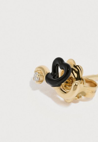 Inel cu ton auriu, având un design răsucit cu un accent negru și o piatră prețioasă transparentă. Textură fină cu forme curgătoare și curbate.