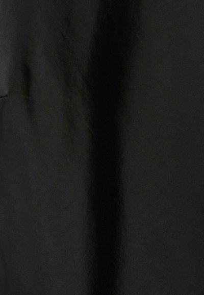 Un tissu noir avec une texture lisse présente un léger éclat et un fin gaufré. La surface semble légèrement froissée avec des plis doux.