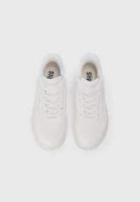 White sneakers with a smooth leather upper, perforated detailing, cushioned collar, and flat laces. Logo visible on tongue and side.