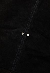 Czarna zamszowa tkanina z dwoma srebrnymi zatrzaskami wzdłuż centralnego szwu, z detalicznym przeszyciem na krawędziach.