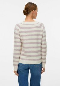 Maglione in maglia oversize con righe in crema chiaro e rosa morbido, maniche lunghe e scollatura ampia. Orlo e polsini a costine. Visuale posteriore mostrata.