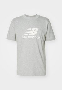Camiseta gris de manga corta de New Balance con logotipo y texto blancos en la parte frontal, exhibida sobre un fondo blanco.