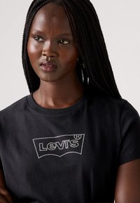 T-shirt in cotone nero con logo Levi's impreziosito da strass, dalla forma classica, con scollatura rotonda e maniche corte.