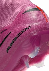 Primo piano di un scarponcino da calcio Nike Air Zoom in rosa con swoosh nero, testo Air Zoom, testo Mercurial arancione e tacchetti traslucidi.