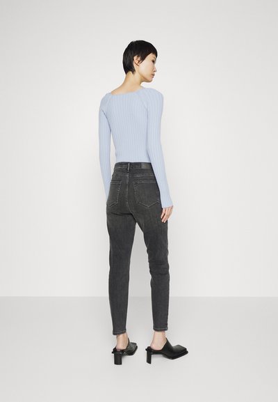 Camisola de manga longa de tom azul claro com nervuras, de corte justo. Combinada com uns jeans de cintura alta cinza escuro e umas mules pretas com biqueira quadrada e salto bloco.