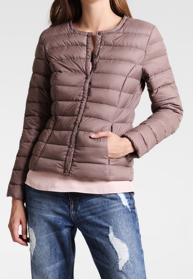 Brun kviltet pufferjakke med rund hals, frontknapper og sidelommer, lagd oven på en lys pink top, parret med slidte jeans.