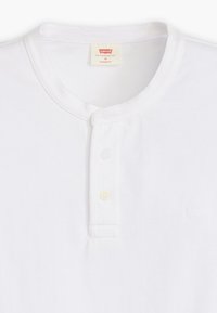 Witte katoenen henley shirt met een ronde halslijn, drie knopen aan de voorkant en subtiele logo borduring op de borst. Standaard pasvorm.